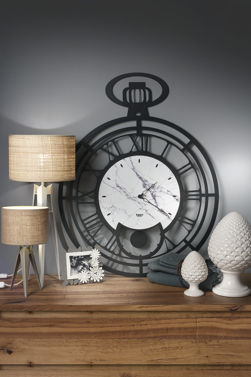 Orologio da parete cipollone ispirato agli orologi da tasca di una volta. Con la sua aria vintage, le sue sottili lancette gli conferiscono una certa aura nostalgia. Realizzato in ferro di colore nero e quadrante con venature che richiamano l’effetto marmo, Dimensione: 80 x 100H cm. In negozio e online su tuttochic.it