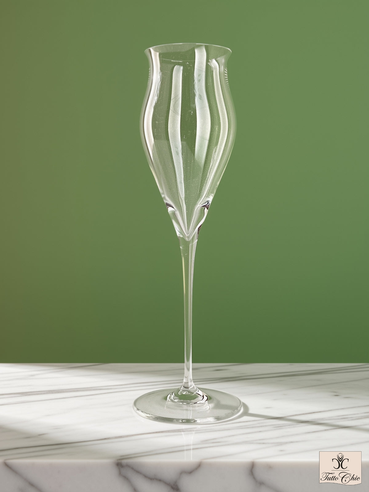 Calice da liquore Spiegelau in vetro soffiato a bocca con stelo alto e coppa svasata, appoggiato su piano in marmo e sfondo verde salvia.