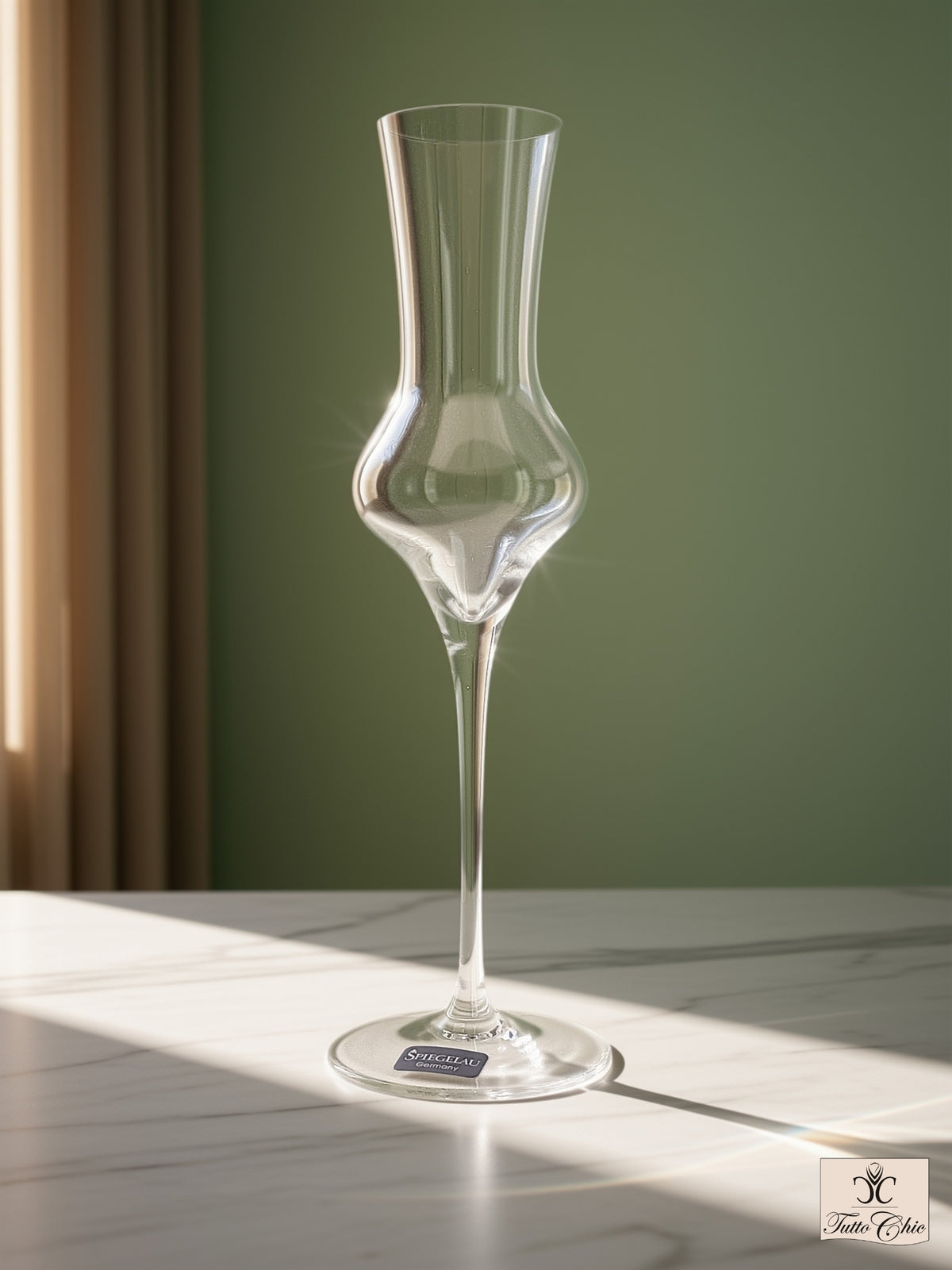 Calice da distillati Spiegelau in vetro soffiato a bocca con stelo alto e sottile, posizionato su piano in marmo e sfondo verde salvia.