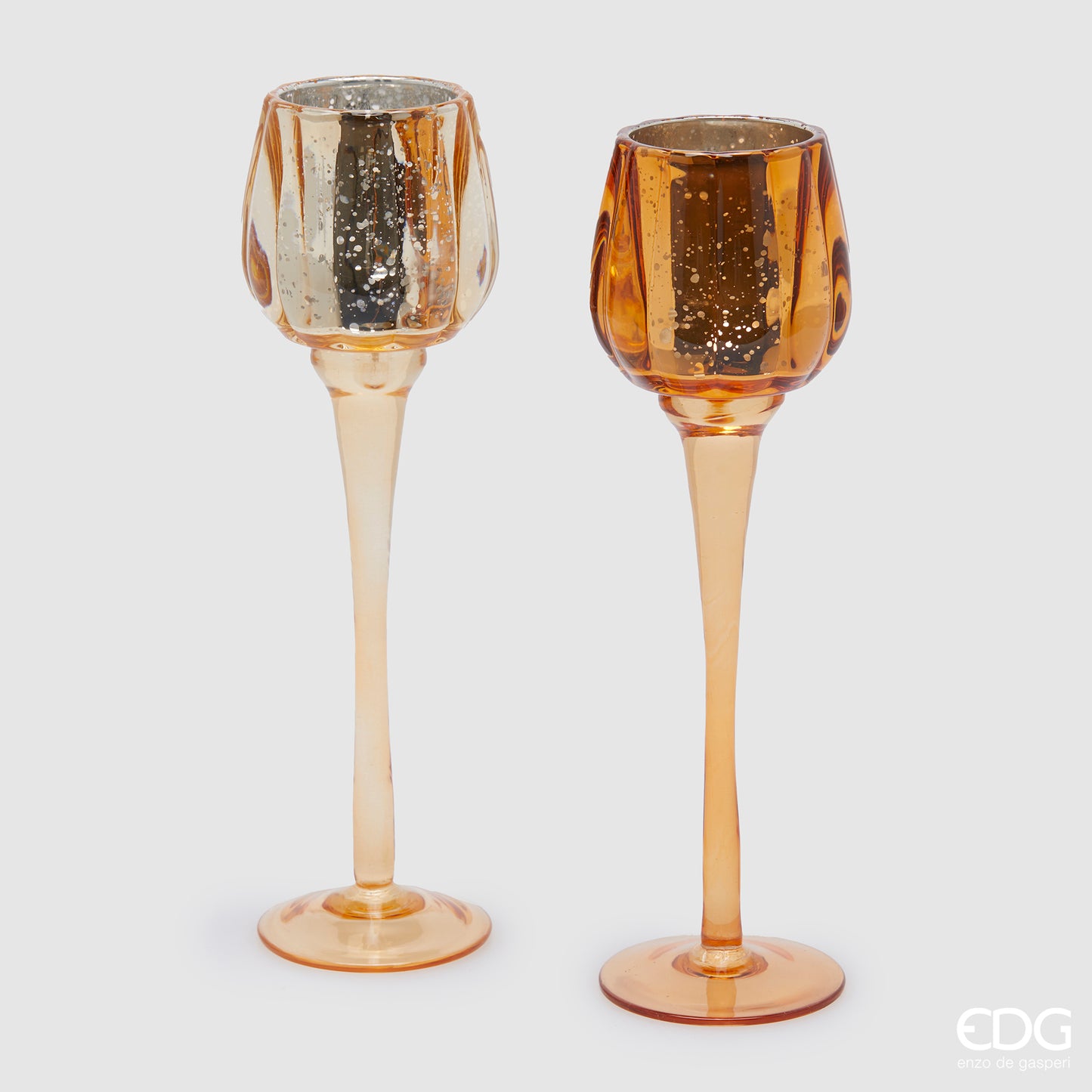 Set di 2 Calici portacandela in vetro lavorato color ambra. Dimensioni: cm h 27,5 x ø 8. Per creare un'atmosfera raffinata ed elegante, si consiglia l'acquisto di più pezzi, di colori e misure diverse. In negozio e online su tuttochic.it