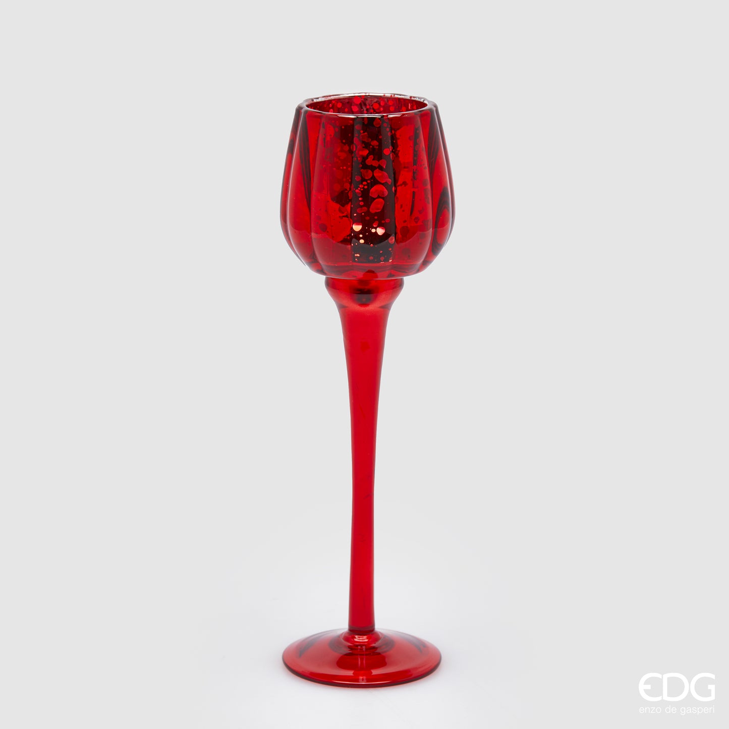 Calice portacandela in vetro lavorato di colore rosso. Dimensioni: cm h 27,5 x ø 8. Per creare un'atmosfera raffinata ed elegante, si consiglia l'acquisto di più pezzi, di colori e misure diverse. In negozio e online su tuttochic.it