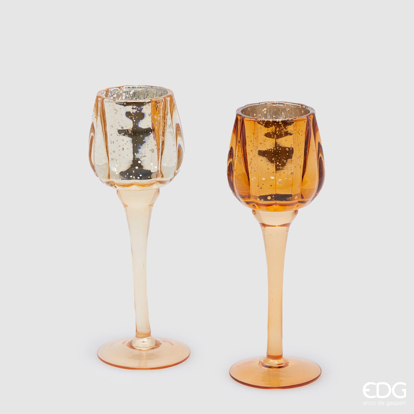 Set di 2 Calici portacandela in vetro lavorato color ambra. Dimensioni: cm h 22 x ø 8. Per creare un'atmosfera raffinata ed elegante, si consiglia l'acquisto di più pezzi, di colori e misure diverse. In negozio e online su tuttochic.it