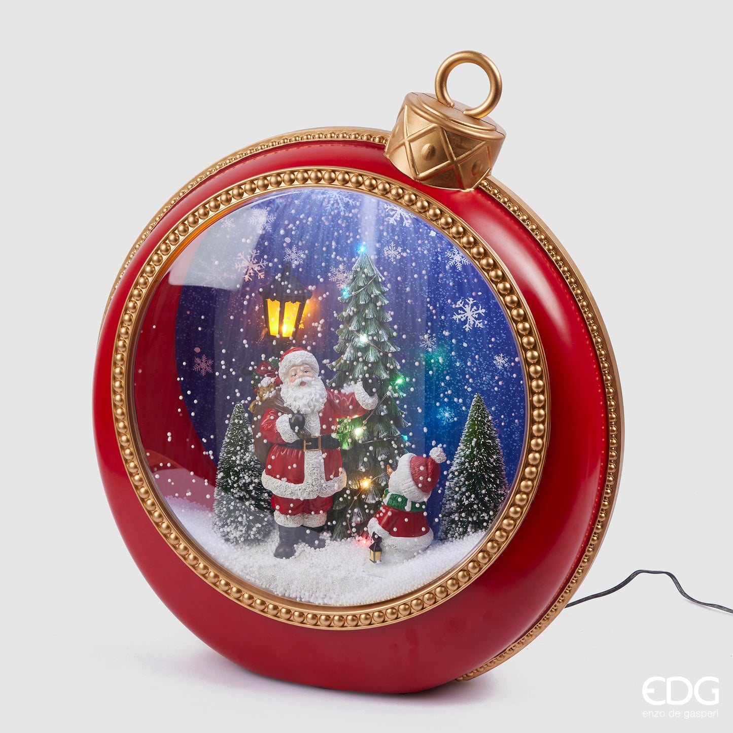 Diorama Babbo Natale con pini, musica e led in plastica a forma di pallina gigante per albero di Natale di colore rosso e particolari dorati. Dimensioni: cm 40 x 15 x h 46. Funziona a corrente, cavo incluso. In negozio e online su tuttochic.it