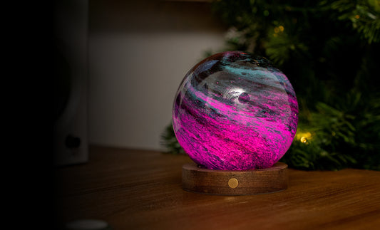 lampada AstraGlass Light. Composta da una sfera in vetro soffiata e dipinta a mano poggiata su una base rotonda in legno di noce americano. Questa lampada è perfetta per chiunque sia affascinato dal meraviglioso fenomeno naturale del nostro mondo. Dimensioni: cm ø 12 x h 13. In negozio e online su tuttochic.it