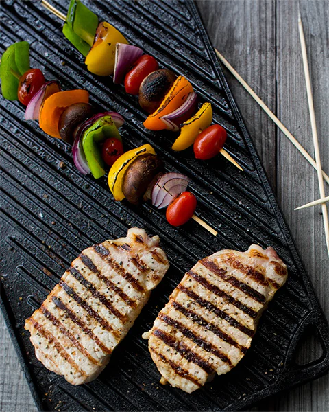 la Piastra Reversibile Lodge. Il lato liscio è ideale per cuocere panini, pancakes, uova e tanto altro. Il lato a coste è adatto invece per grigliare carne, pesce e verdure di ogni tipo. Resiste alle altissime temperature. Dimensione: 42,55 x 24,13 x 1,57 cm• Peso: 4,25 kg. In negozio e online su tuttochic.it