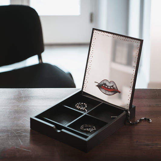 Aggiungi un tocco di fortuna e stile al tuo spazio con il Portagioie Bocca con Peperoncino dalla linea "The Spicy Riot". Questo portagioie moderno e sofisticato è dotato di uno specchio per facilitare il tuo trucco e la sua decorazione iconica ti porterà fortuna. cm 21 x 26 x 3,8. In negozio e online su tuttochic.it