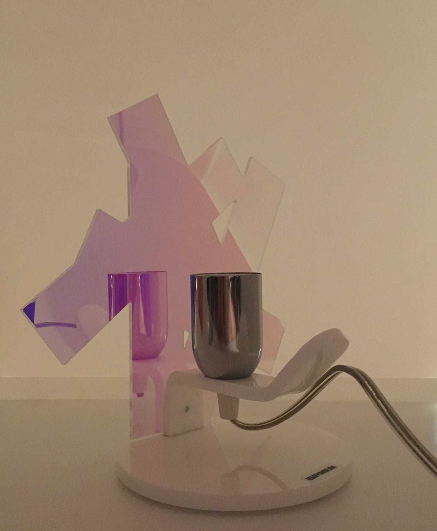 Lampada da tavolo in metacrilato dalla colorazione particolare flash (effetto specchio iridescente). Base e supporto in metacrilato bianco e portalampadina in metallo cromato. Si può applicare qualsiasi lampadina con attacco filettato E 27 (non inclusa). Dimensioni: cm 23 x 23 x 15 p. In negozio e online su tuttochic.it