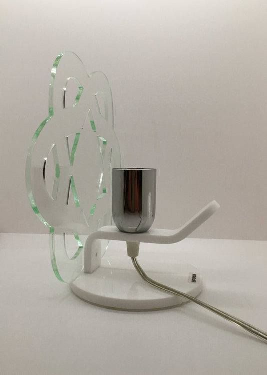 Lampada da tavolo in metacrilato trasparente con profilo verde soft. Base e supporto in metacrilato bianco e portalampadina in metallo cromato. Si può applicare qualsiasi lampadina con attacco filettato E 27 (non inclusa). Dimensioni: cm 23 x 23 x 15 p. In negozio e online su tuttochic.it