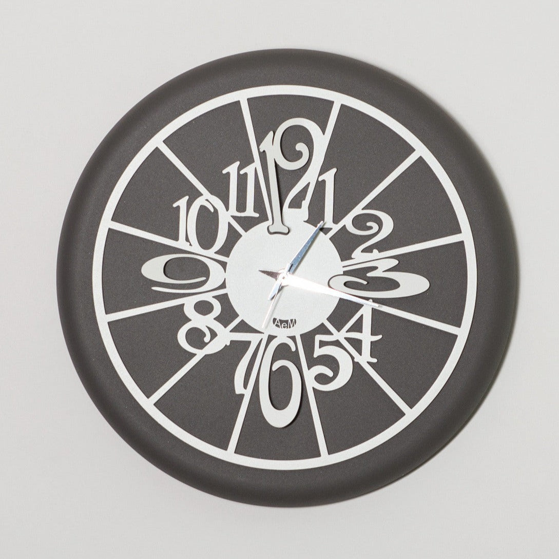 Orologio da parete di dimensione contenute, simpatico e divertente, fondo di colore ardesia, facile da collocare in cucina. Dimensioni: diam.30. In negozio e online su tuttochic.it