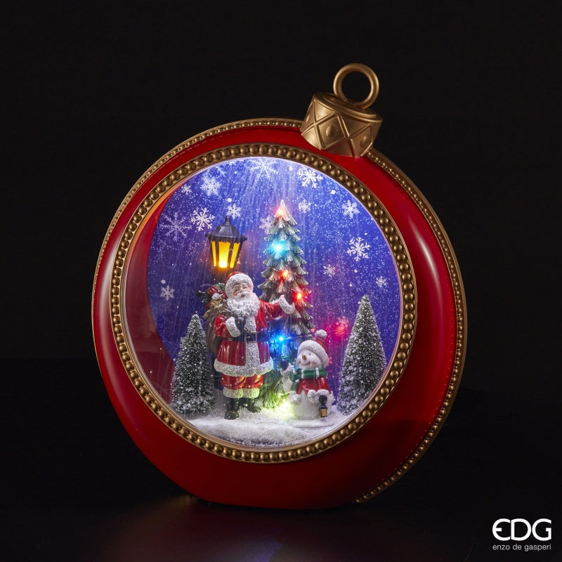 Diorama Babbo Natale con pini, musica e led in plastica a forma di pallina gigante per albero di Natale di colore rosso e particolari dorati. Dimensioni: cm 40 x 15 x h 46. Funziona a corrente, cavo incluso. In negozio e online su tuttochic.it