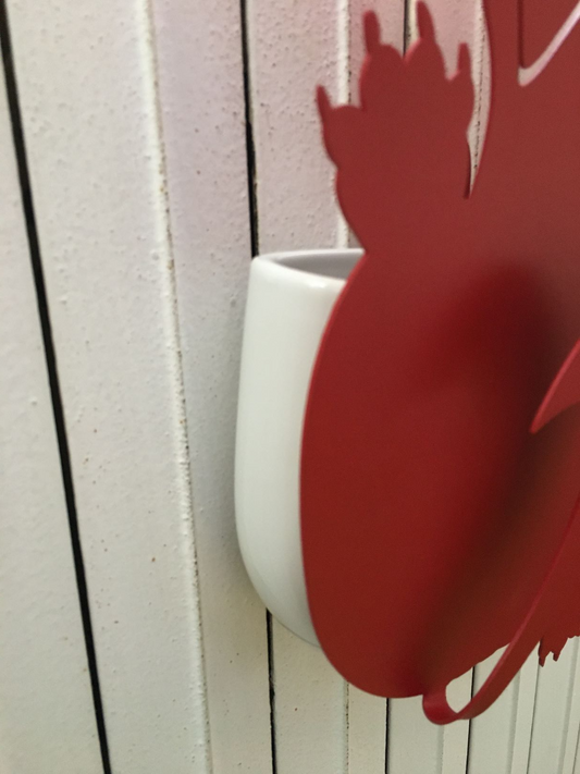 Umidificatore in metallo di colore rosso. Corredato di un contenitore in porcellana per l'acqua e il gancio in metallo per appenderlo a qualunque radiatore. Dimensioni: 22 x 5 x h 40 cm