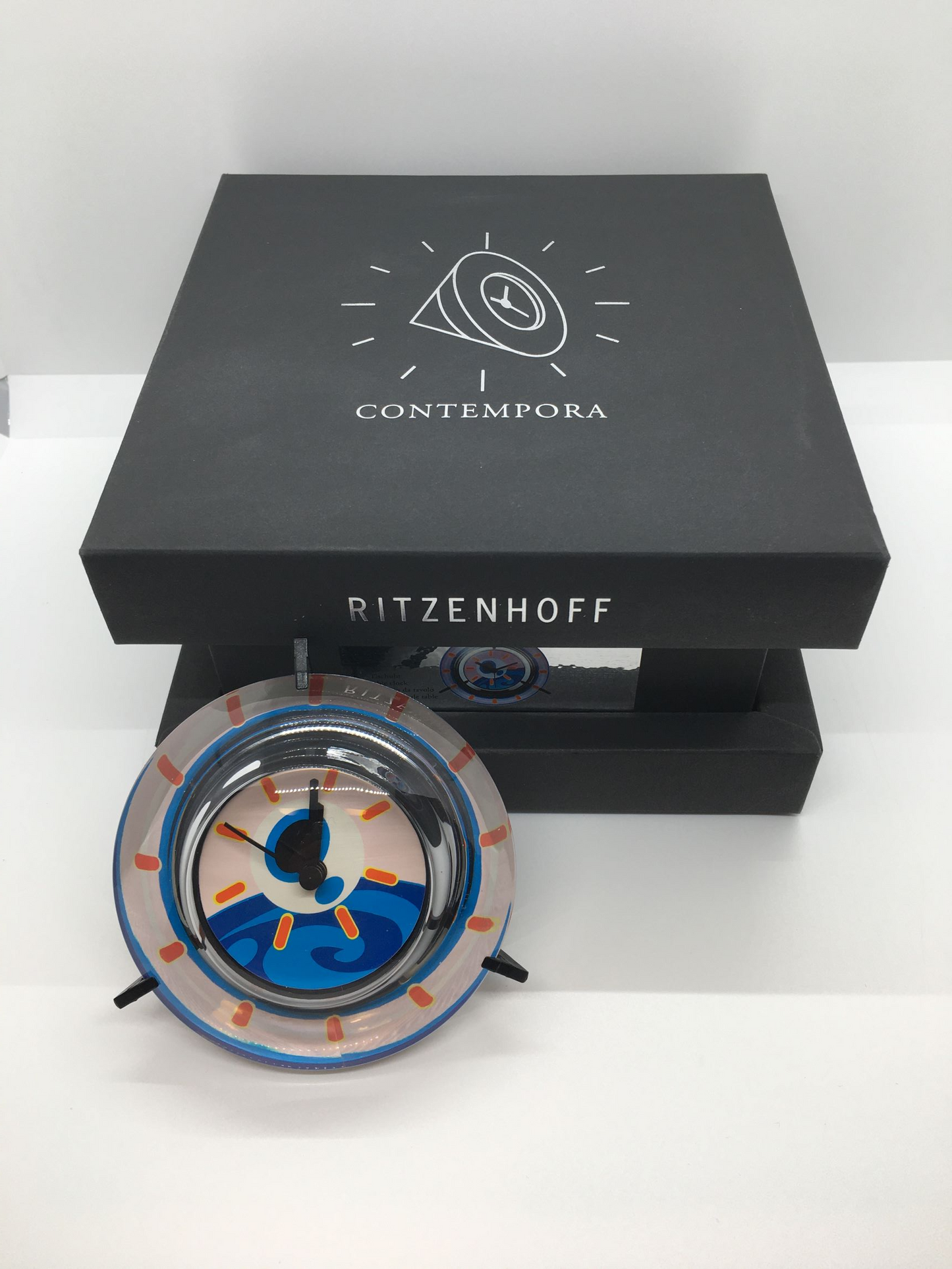 Orologio da tavolo in cristallo con decoro progettato da Beppe Facente nel 2000, Edizione Limitata, della linea "Contempora" di Ritzenhoff. Custodito in una scatola di cartone su cuscino di velluto nero. Dimensioni (orologio): cm 10 x 8 h Funzionamento a batteria (inclusa)