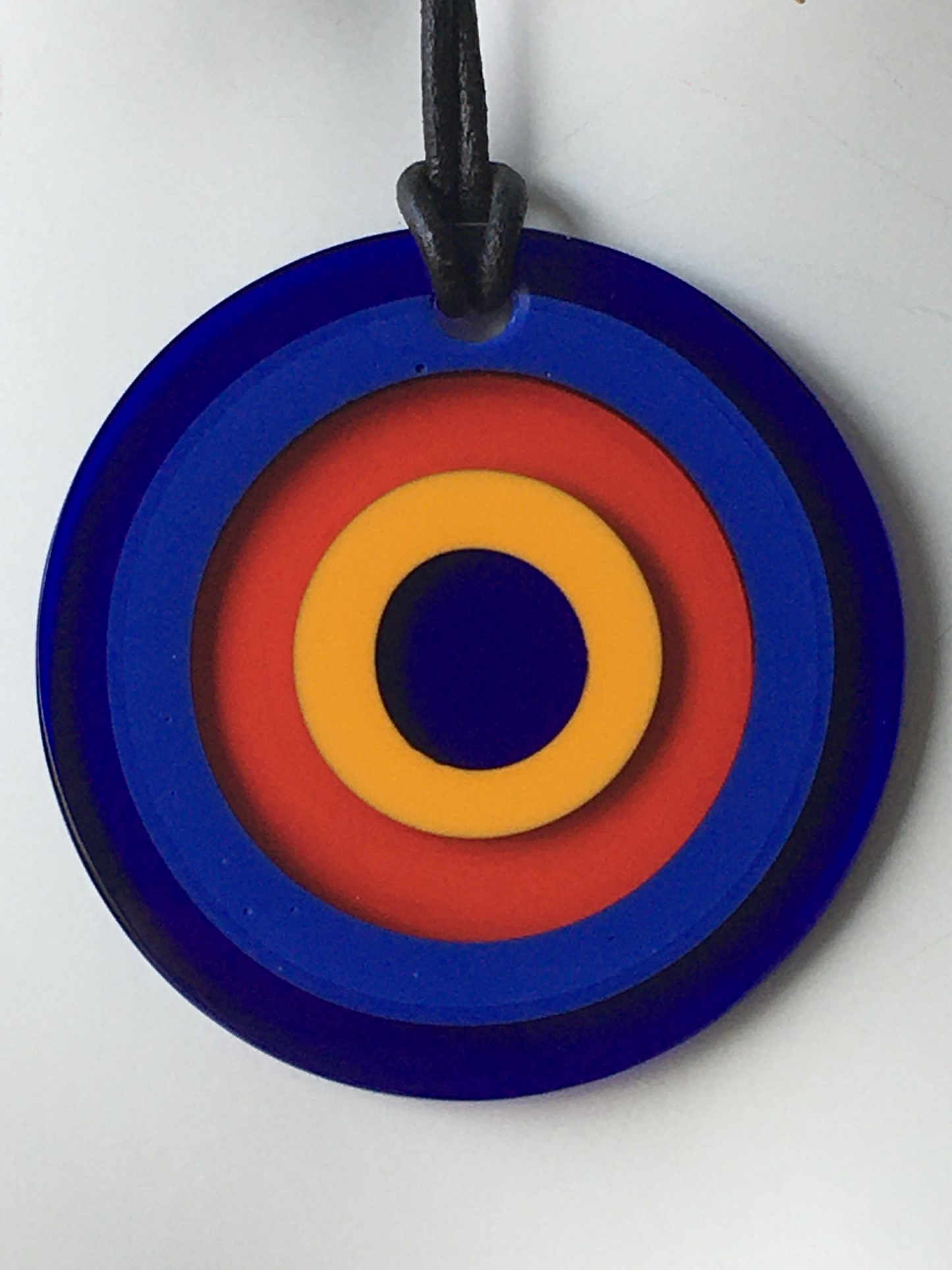 Pendente in cristallo di Murano rifinito a mano con motivi decorativi applicati a caldo: murrina ad anelli. Dotato di laccetto in cuoio. Dimensioni: diametro cm 6,5
