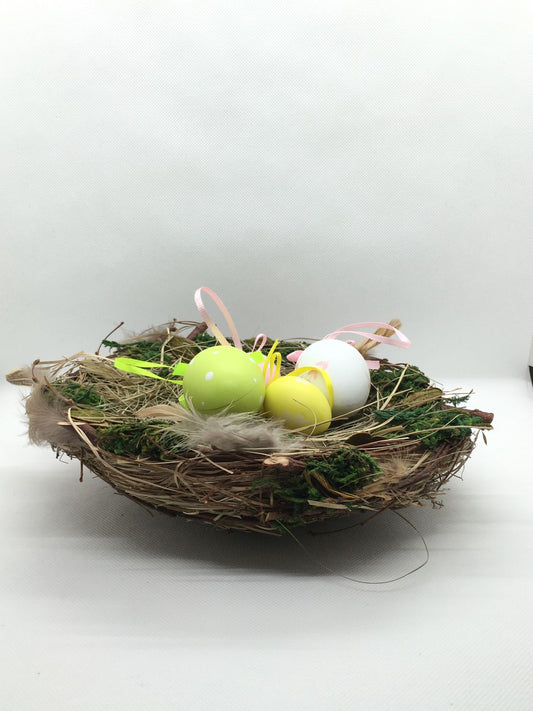 Nido fatto con materiali naturali e con 4 uova in plastica decorata (la decorazione delle uova è varia e assortita). Dimensioni: diametro cm 20, altezza cm 8