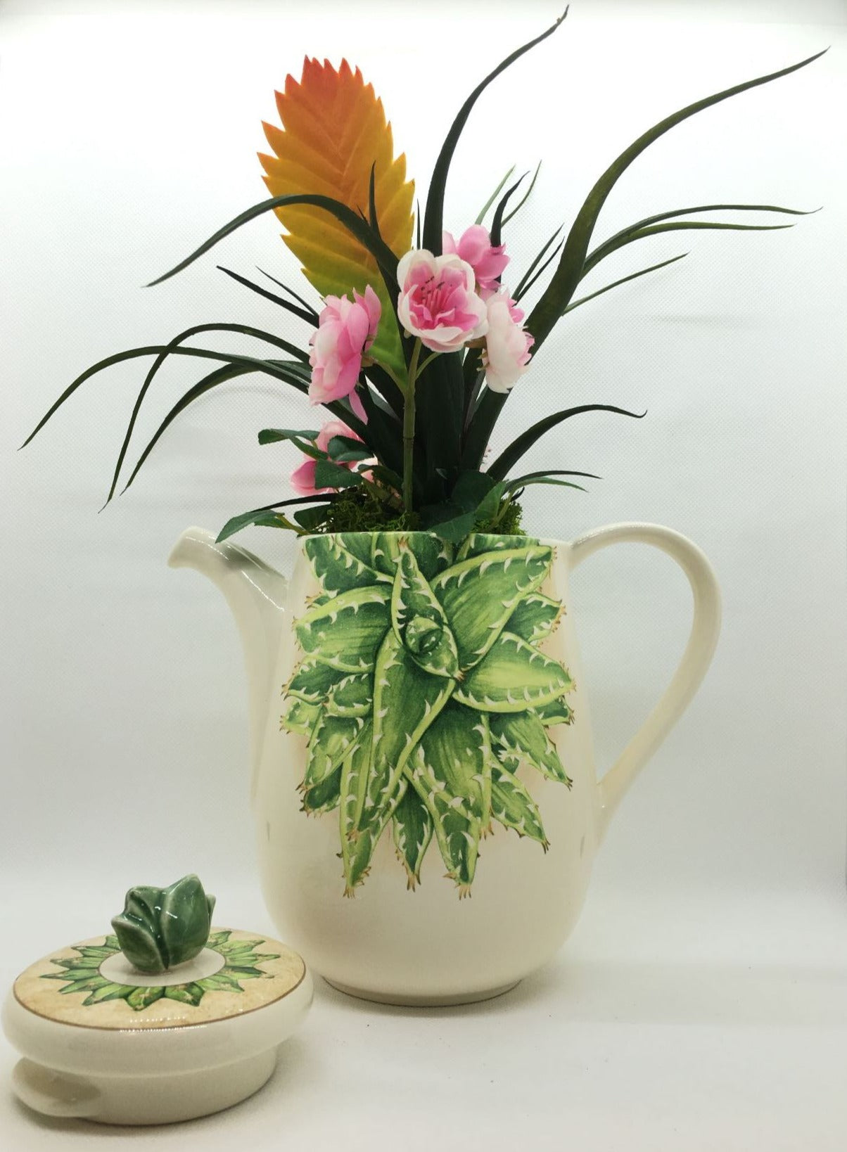 Caffettiera a servire in ceramica decorata con composizione floreale artificiale, completa di coperchio. Made in Italy Dimensioni: (totali cm 30 x 34 h) solo caffettiera cm 20 x 18 h. In negozio e online su tuttochic.it