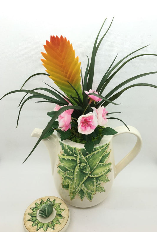 Caffettiera a servire in ceramica decorata con composizione floreale artificiale, completa di coperchio. Made in Italy Dimensioni: (totali cm 30 x 34 h) solo caffettiera cm 20 x 18 h. In negozio e online su tuttochic.it