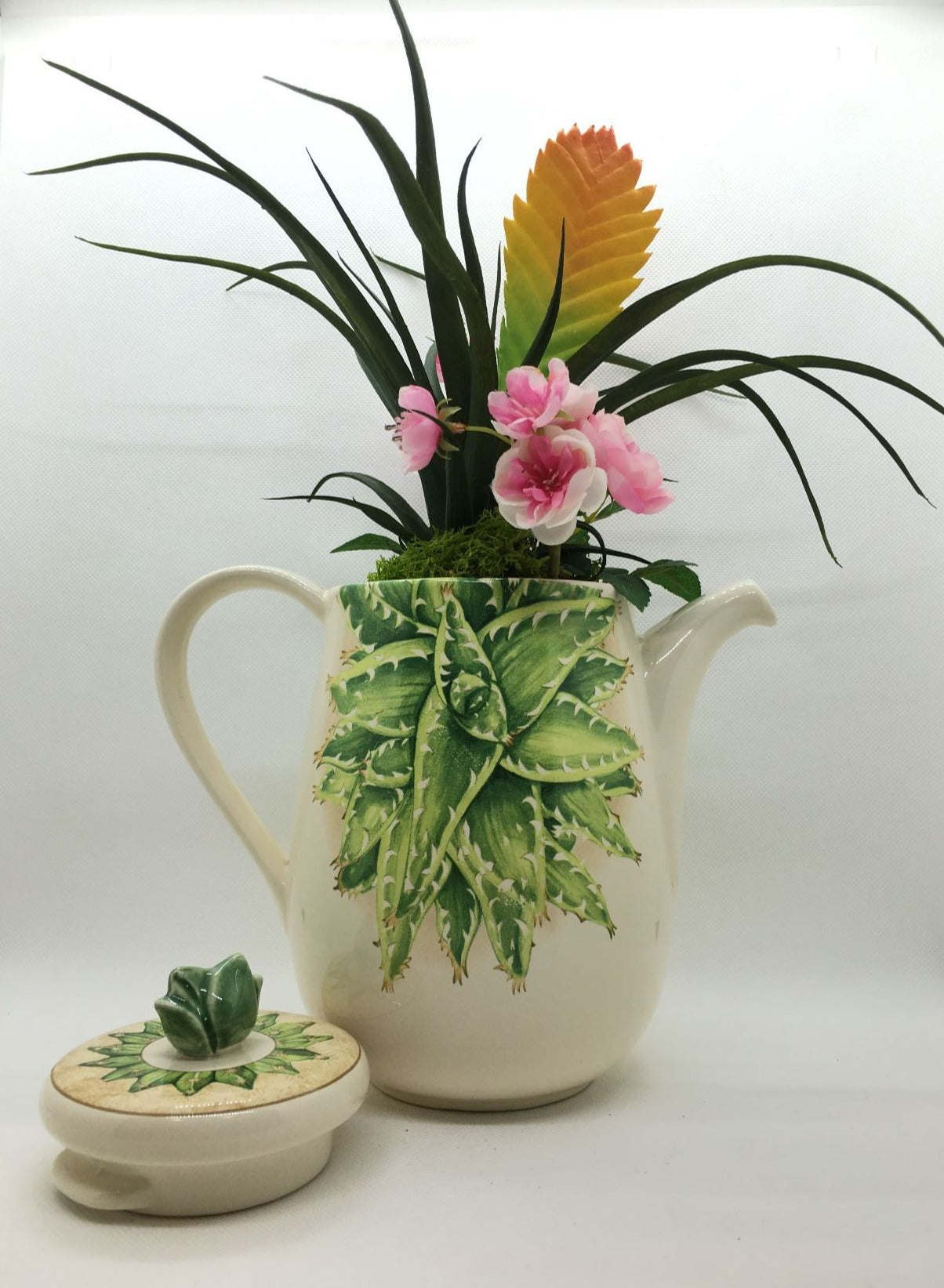 Caffettiera a servire in ceramica decorata con composizione floreale artificiale, completa di coperchio. Made in Italy Dimensioni: (totali cm 30 x 34 h) solo caffettiera cm 20 x 18 h. In negozio e online su tuttochic.it