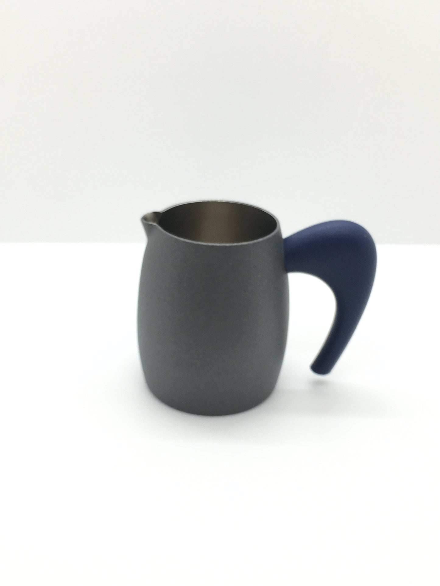 Lattiera in acciaio inox lucido all'interno e brunito all'esterno con manico in plastica di colore blu scuro. Dimensioni: cm 9 (con manico) x 6 x 7 h. In negozio e online su tuttochic.it