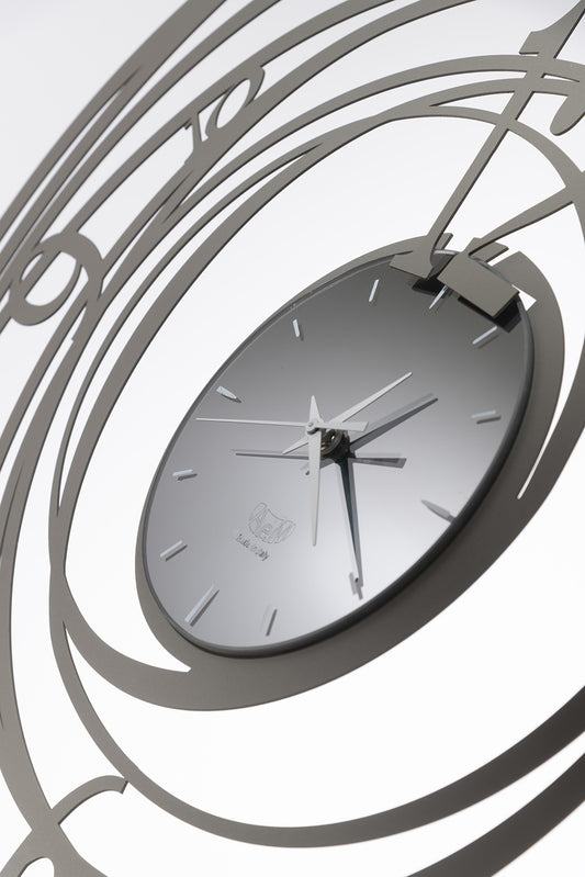 Orologio da parete in metallo verniciato a polvere epossidica di colore fango. Ghirigoro è un orologio da parete la cui particolarità sono le linee circolari che si sviluppano dal quadrante interno fino a formare una cornice tutto intorno. Il quadrante centrale è piccolo e minimal. Dimensioni: diametro 70 cm