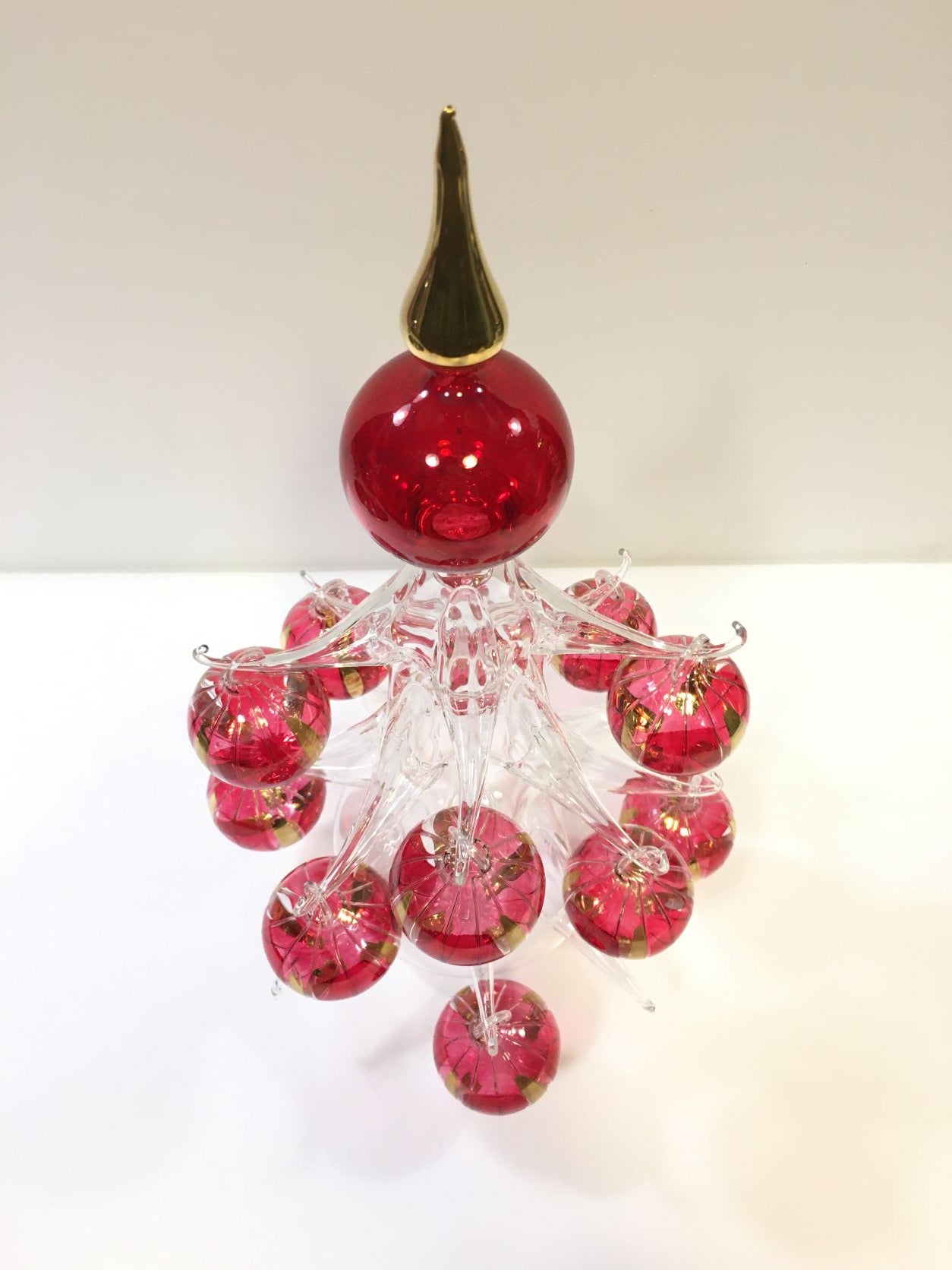 Abete in vetro soffiato con 12 palline rosso/oro, prodotto lavorato, rifinito e decorato completamente a mano. Made in Italy. Dimensioni: cm 22 x 39 h. In negozio e online su tuttochic.it