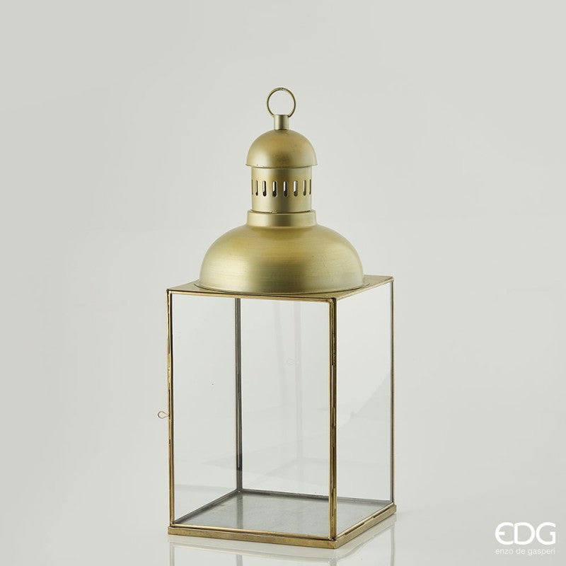 Lanterna quadrata con cupola in metallo di colore oro opaco con effetto invecchiato e vetro. Dimensioni: cm 30 x 30 x 76 h. In negozio e online su tuttochic.it
