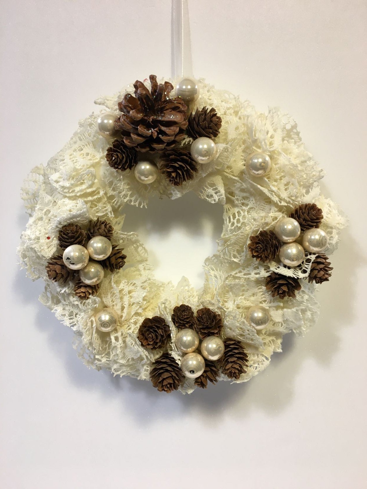 Ghirlanda in tessuto pizzo bianco e arricchito di pigne e palline in vetro. Dimensioni Lung x Larg x Alt cm : 28 x 8 x 28. In negozio e online su tuttochic.it