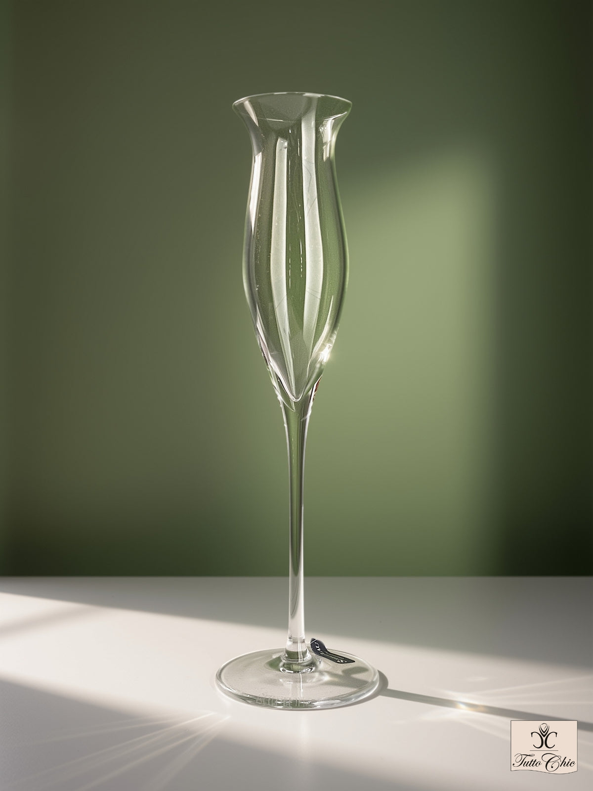 Calice da grappa Spiegelau in vetro soffiato a bocca con stelo alto e coppa svasata a tulipano, su piano bianco e sfondo verde salvia.