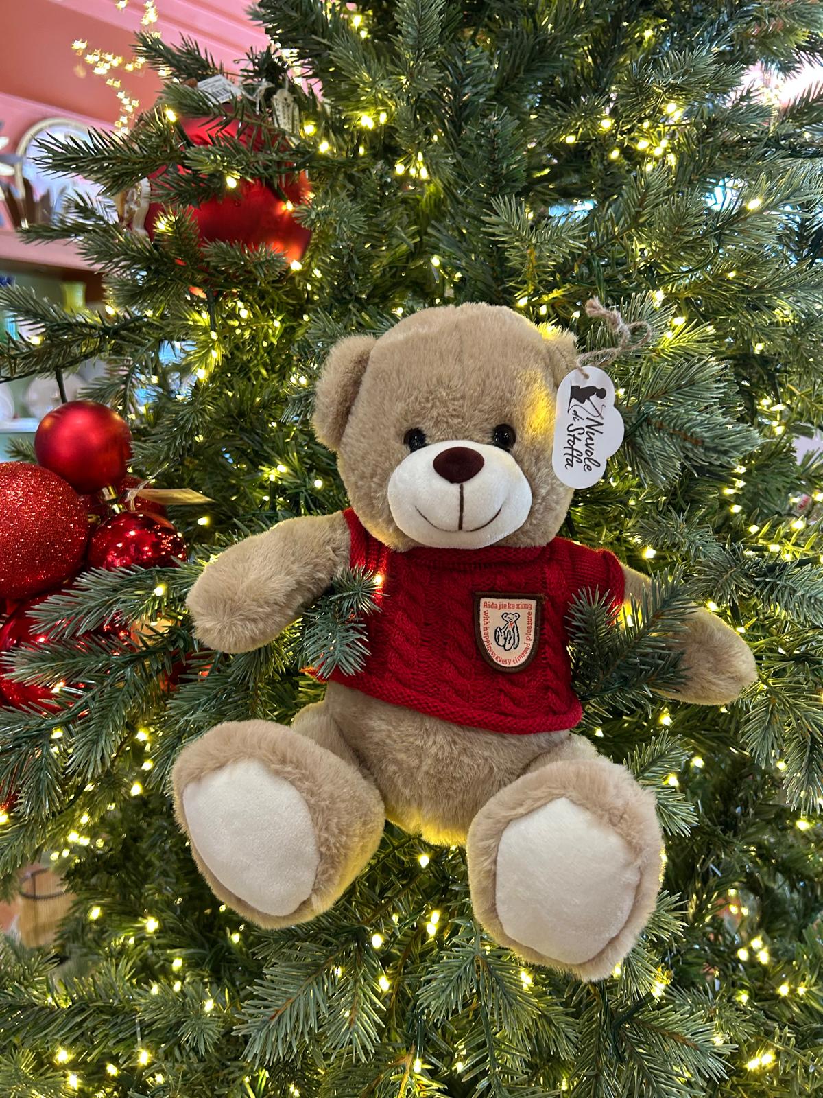 Splendido orsetto peluche "Bear Wonderland", vestito con un maglione colorato in morbido cotone e poliestere. Crea un'atmosfera natalizia con il nostro adorabile orsetto, perfetto come regalo o come decorazione per la tua casa. Dimensioni: cm 25. In negozio e online su tuttochic.it