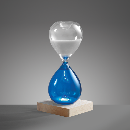 Clessidra in vetro bicolore blu/trasparente con base in legno illuminata a led. Durata di 30 minuti circa, corredata di cavetto di alimentazione USB. Dimensioni: cm 10 x 10 x 21 h. In negozio e online su tuttochic.it