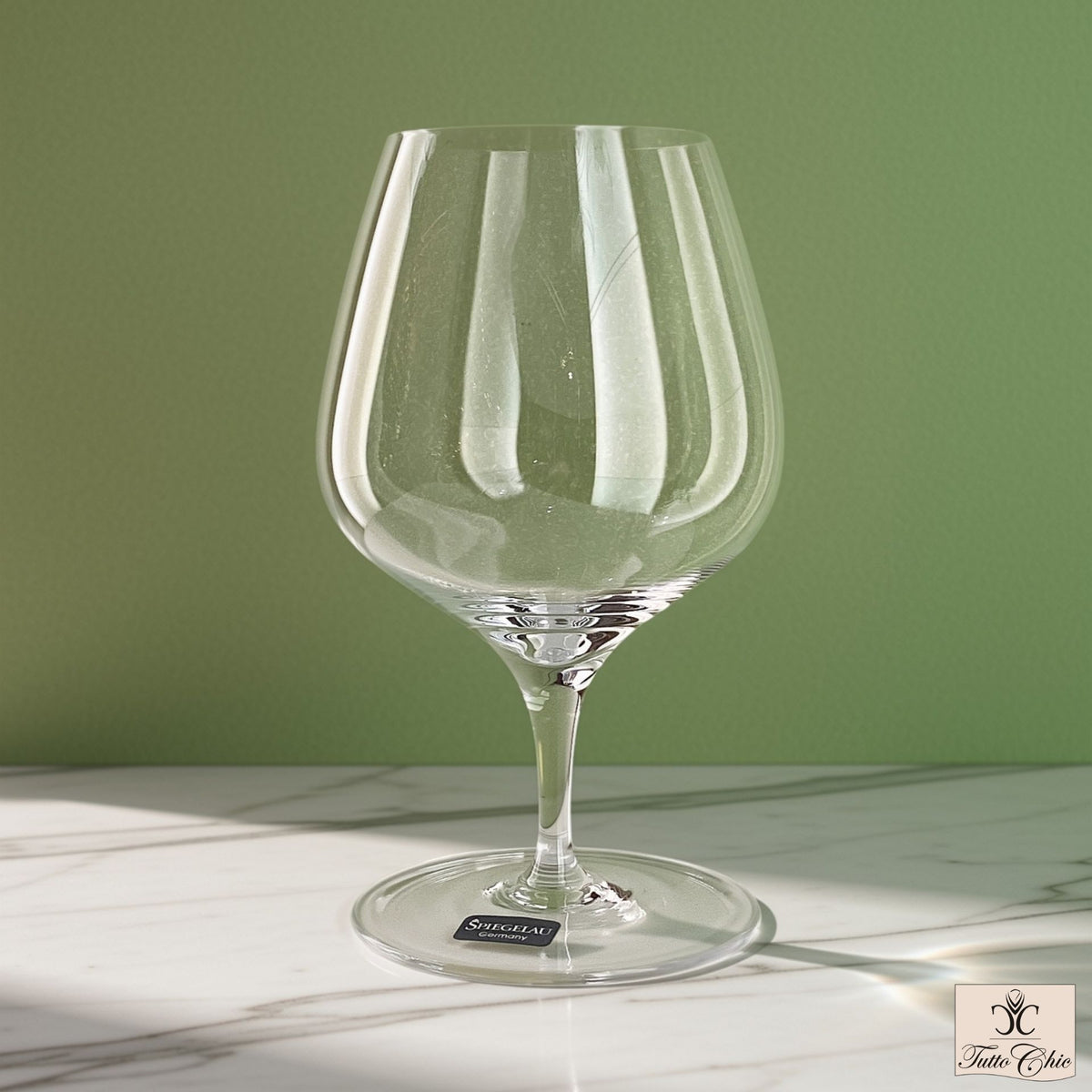 Calice ballon da degustazione cognac Spiegelau della linea Adina soffiati a bocca su ripiano in marmo con sfondo verde chiaro.