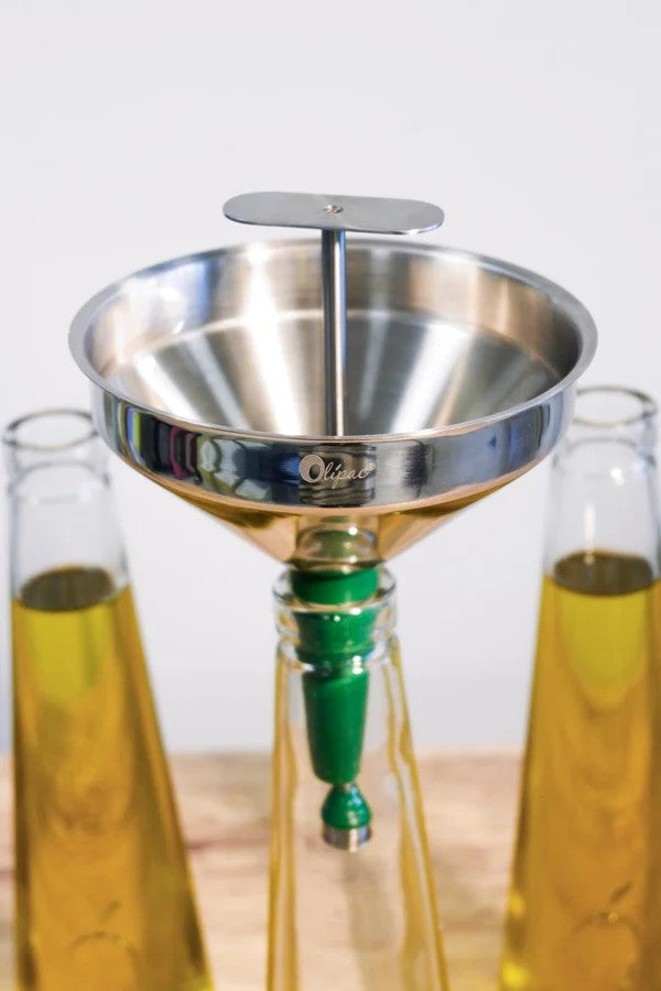 Imbuto in acciaio inox Ipac Olipac inserito sul collo di una bottiglia in vetro trasparente per olio