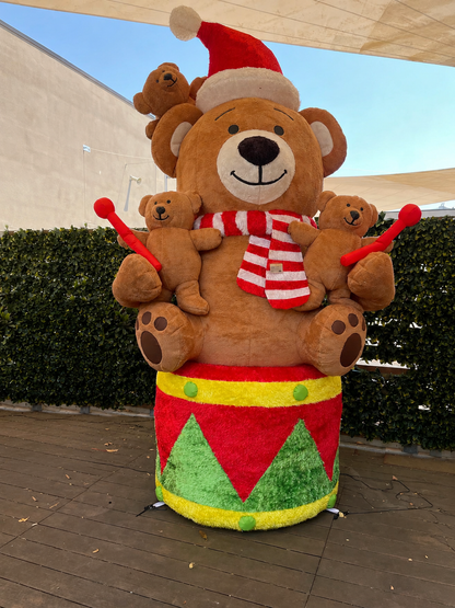 Maxi orso gonfiabile natalizio da esterno EDG alto 280 cm, seduto su un tamburo festivo con orsetti piccoli, sciarpa a righe e cappello di Babbo Natale su sfondo chiaro.