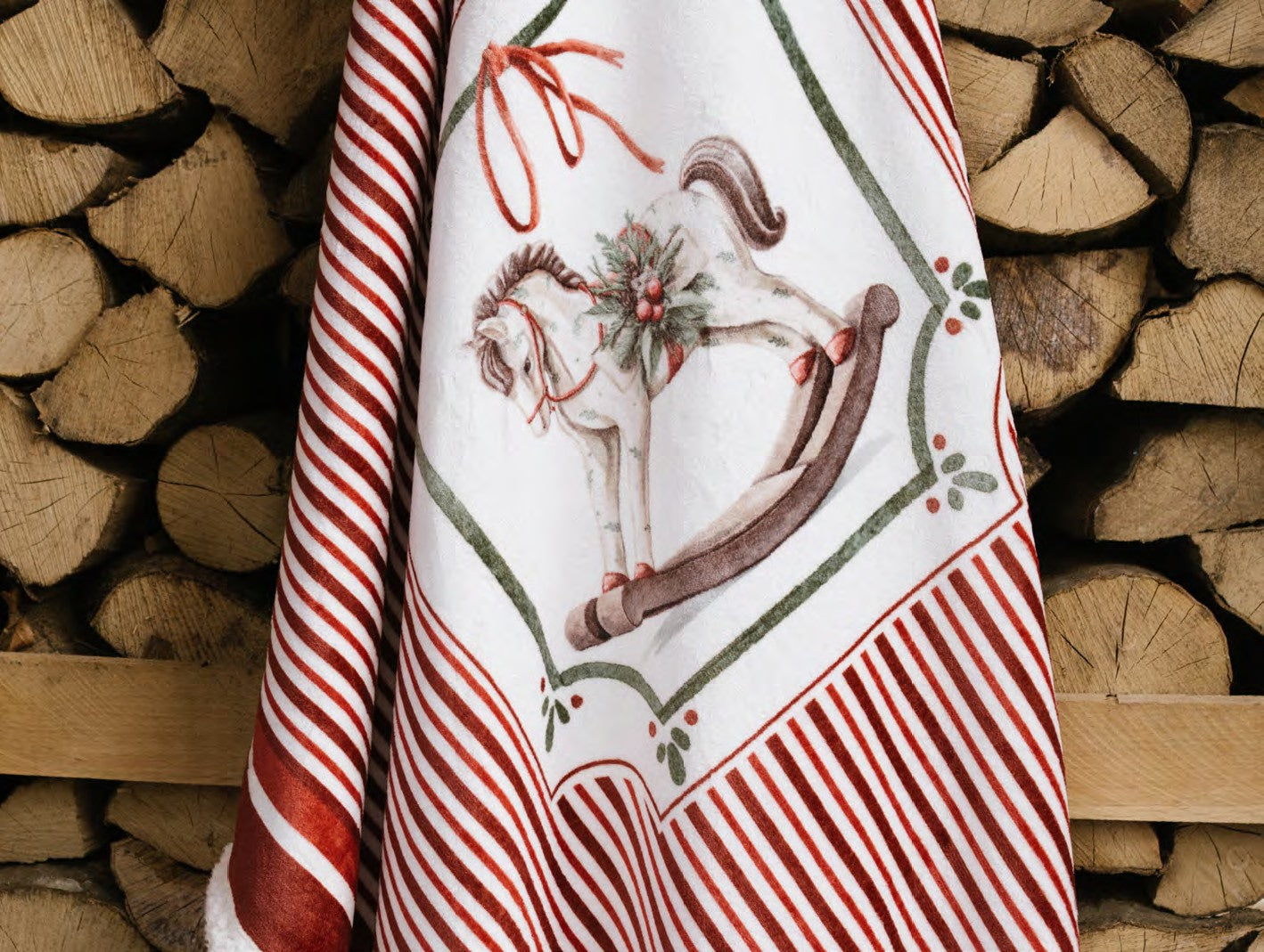 Esclusivo plaid natalizio Magic Noel di Nuvole di Stoffa ripiegato nella sua scatola regalo rigida, motivo a righe bianche e rosse con cavallo a dondolo, Tutto Chic.
