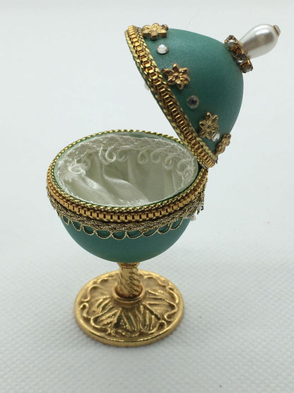Vero uovo di quaglia lavorato e decorato di colore turchese, apribile porta gioie. Dimensioni: diametro interno cm 3 x 6,7 h esterno