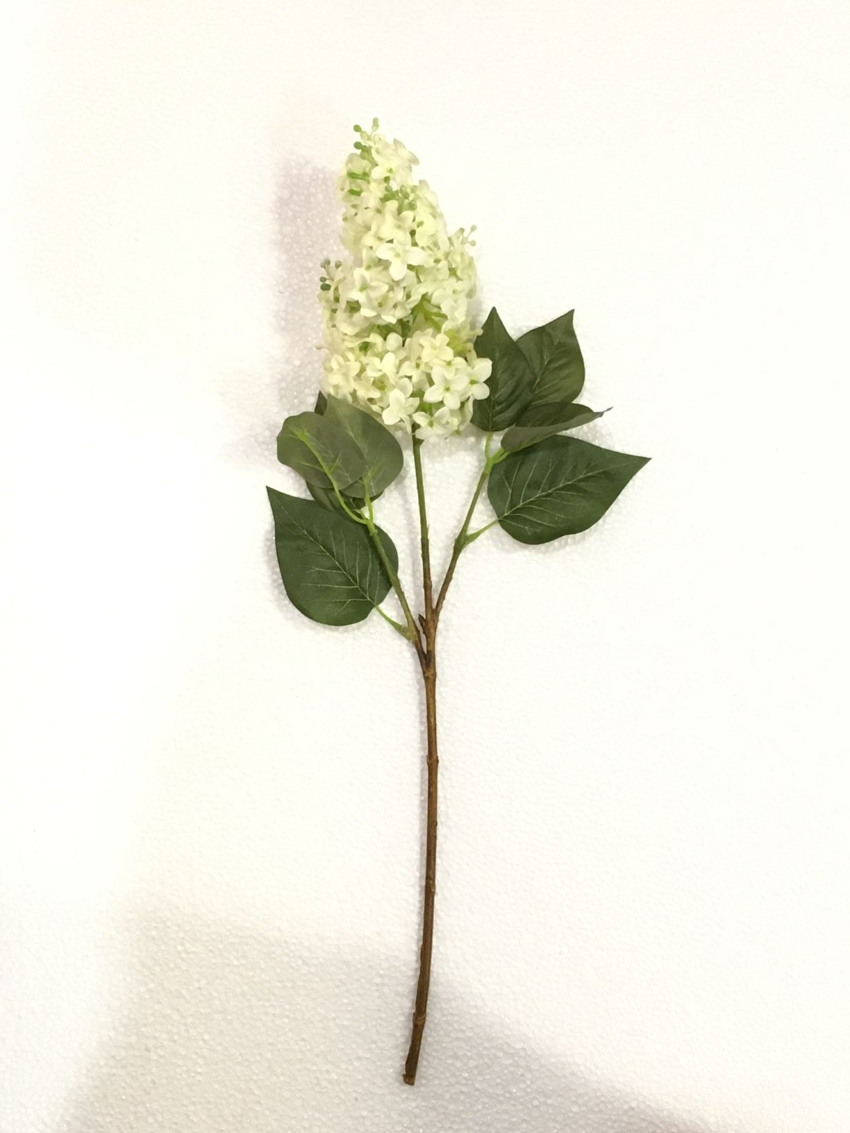 Fiore artificiale Lillà Eden di colore bianco. Dimensioni: cm 52. Petali e foglie in tessuto, rametti in plastica. In negozio e online su tuttochic.it