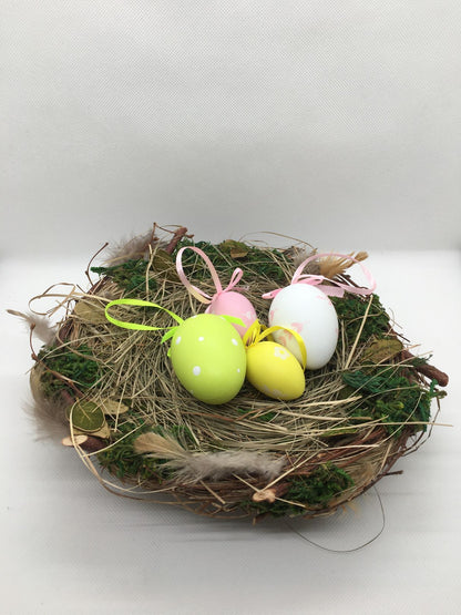 Nido fatto con materiali naturali e con 4 uova in plastica decorata (la decorazione delle uova è varia e assortita). Dimensioni: diametro cm 20, altezza cm 8
