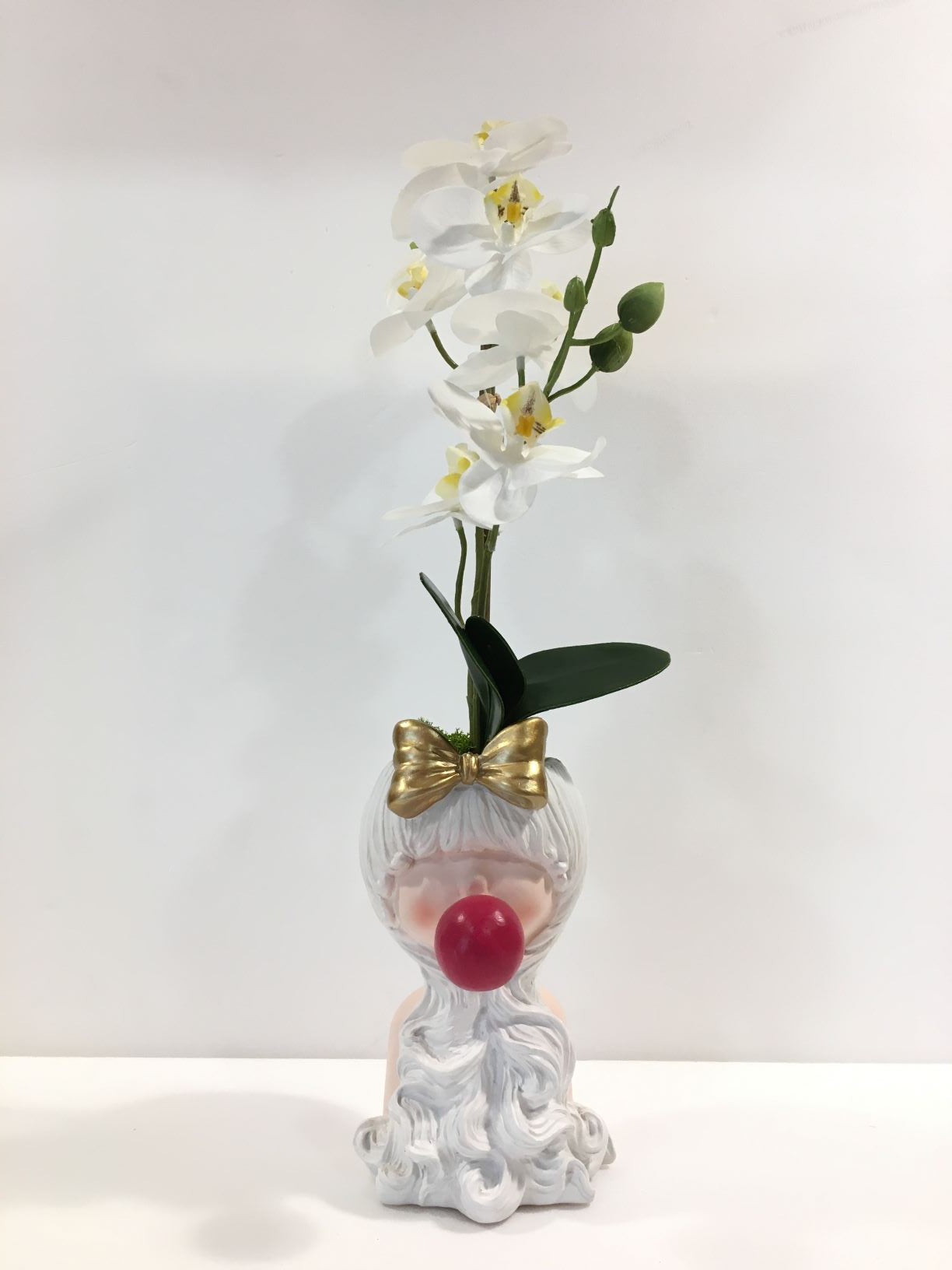 Vaso Sakura fiocco oro in resina decorata con composizione di orchidee artificiali. Dimensioni totali: cm 15 x 13 x 50 h. In negozio e online su tuttochic.it