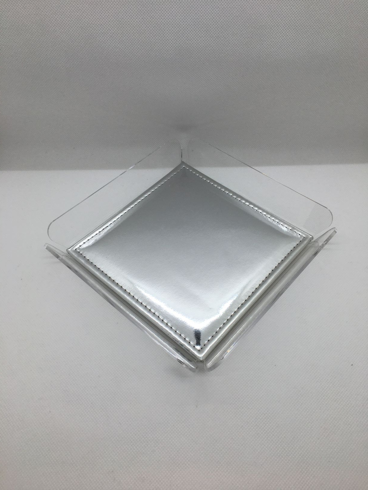 ANYTHING Vuotatasche in cristallo acrilico trasparente con cuscinetto argento. Dimensioni cm 18x18x3 h. Spessore PMMA mm 3. In negozio e online su tuttochic.it