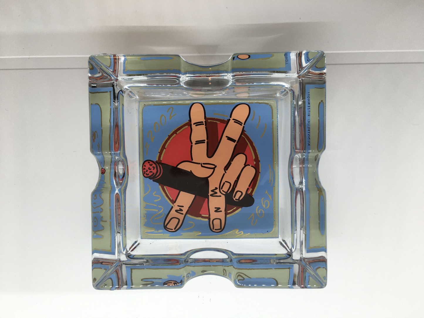Posacenere quadrato in cristallo con decoro progettato da Kunstflug nel 2002, Edizione Limitata, della linea "Smoking Xclusive" di Ritzenhoff. Custodito in una scatola di legno con cerniere e chiusura in metallo Dimensioni: mm. 100 x 100