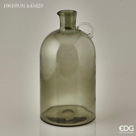 Vaso bottiglia con manico in vetro di colore verde scuro traslucido.  Dimensioni: altezza cm. 43, diametro cm. 23  Articolo decorativo, non adatto a uso alimentare.