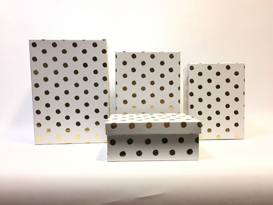 Set di 4 scatole regalo rettangolari in cartone bianco con decorazione pois color oro. Dimensioni: scatola piccola cm 18 x 13 x 7,7 h scatola media cm 20 x 14,5 x 8,5 h scatola grande cm 23 x 16,5 x 10,4 h scatola maxi cm 26 x 18,5 x 12 h. In negozio e online su tuttochic.it